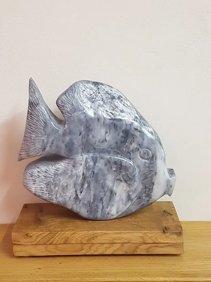 Beeld van een vis in speksteen op een houten voet