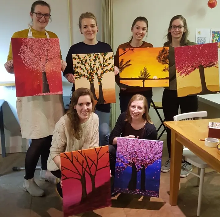 Een groep vriendinnen met hun schilderijen van bomen